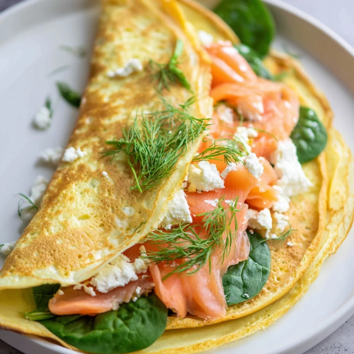 Frothy, golden-brown blender egg crepe wrap, filled with fresh spinach and smoked salmon, ready to eat!