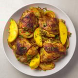 A close-up of a sheet pan German-Style Chicken, featuring crispy chicken and caramelized onions ready to eat.