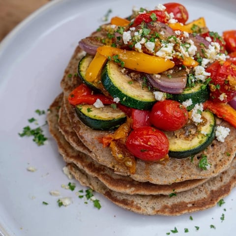 Golden-brown savory buckwheat pancakes with colorful roasted vegetables, ready to eat.
