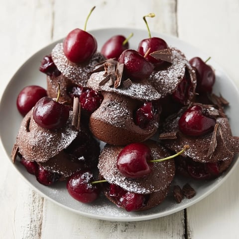 Fluffy Black Forest Pancake Minis stacked high, drizzled with cherry compote and whipped cream.