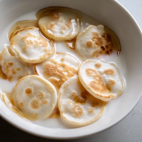 Fluffy pancake cereal, adorable mini pancakes golden brown, ready to be drizzled with syrup.