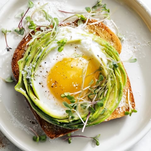 Fluffy baked egg white "Cloud Toast 2.0" sits on golden toast, crowned with avocado.