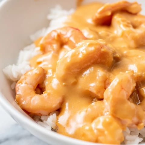 Ein heißer, cremiger Cajun-Garnelen-Reis-Schüssel wird mit duftendem Jasminreis serviert und mit Zitronensaft beträufelt.