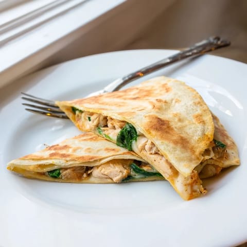 A close-up of a sizzling Chicken and Spinach Quesadilla, revealing tender chicken and wilted greens inside.