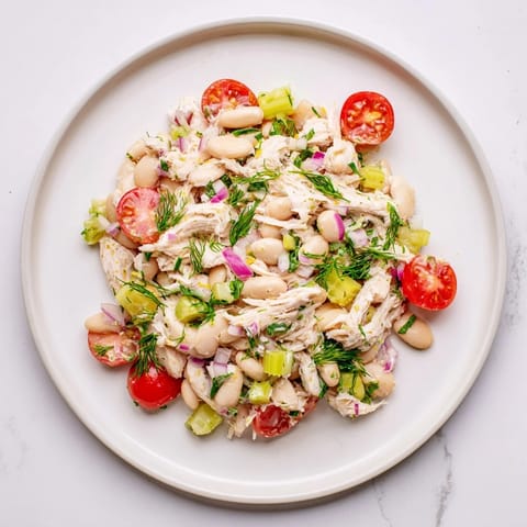 Ein farbenfroher Teller mit Lemony White Bean Chicken Salad, gewürfelt mit knackigem Sellerie, weißen Bohnen und frischen Kräutern.