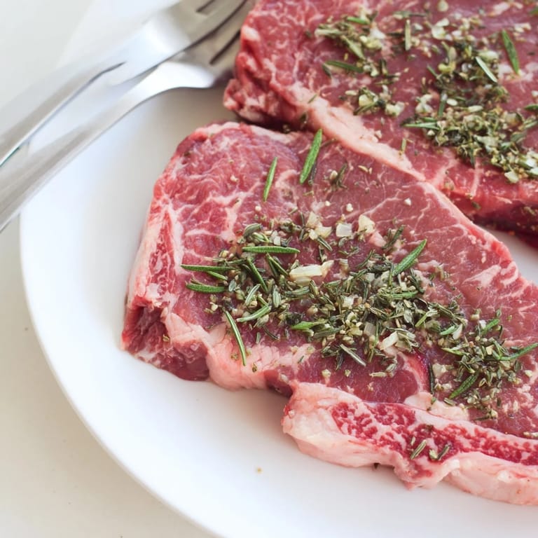 Zarte, duftende Kräuterbraten, angerichtet mit Rotwein und Zwiebeln für Genuss.