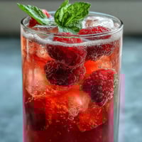 1. Raspberry Lime Spritz: A bubbly cocktail with fresh raspberries, zesty lime, and sparkling wine, garnished with mint and lime wedges.  